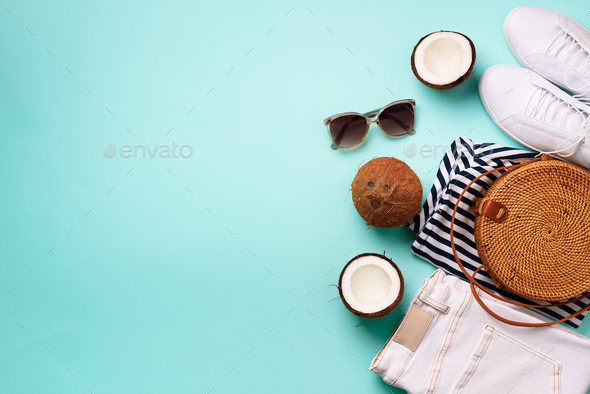 Female white sneakers, jeans, striped t-shirt, rattan bag, coconut and sunglasses on blue background - Stock Photo - Images