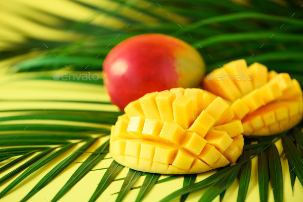 Exotic mango fruit over tropical green palm leaves on yellow background. Copy space. Pop art design - Stock Photo - Images