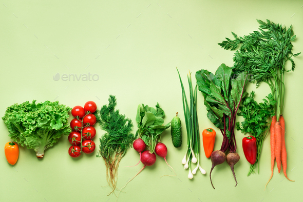 Organic vegetables and garden tools on green background with copy space. Top view of carrot, beet - Stock Photo - Images
