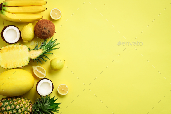 Fresh organic yellow fruits over sunny background. Monochrome concept with banana, coconut - Stock Photo - Images