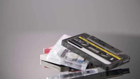Audio cassettes rotating on a reflective surface in a studio shot. Close up