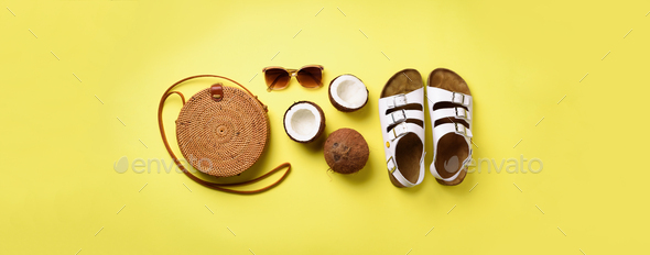 Stylish rattan bag, coconut, birkenstocks, palm branches, sunglasses on yellow background. Banner - Stock Photo - Images