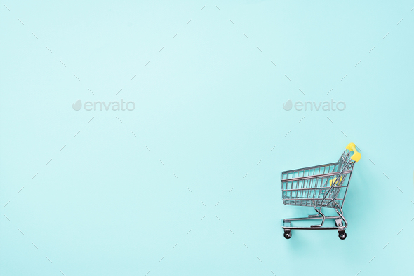 Shopping cart on blue background. Minimalism style. Creative design. Top view with copy space. Shop