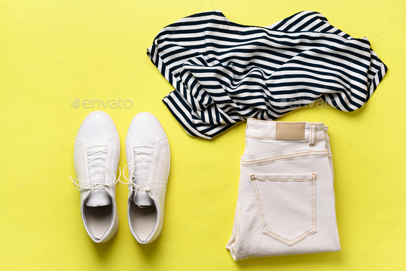 Female white sneakers and jeans, striped t-shirt on yellow background with copy space. Top view - Stock Photo - Images