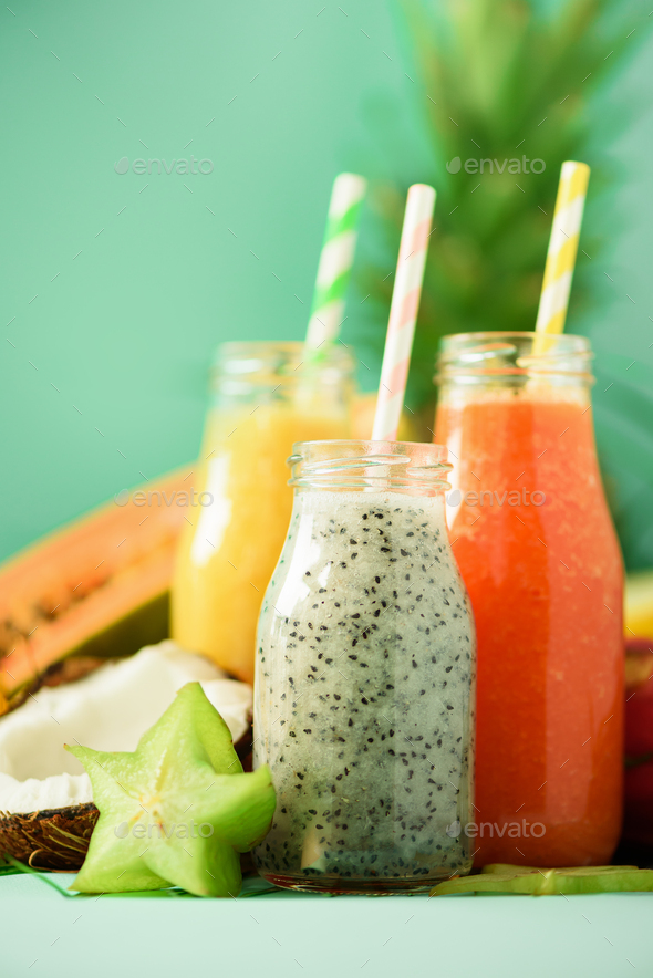 Papaya, dragon fruit, pineapple, mango smoothie in jars on turquoise background. Detox, vegan diet - Stock Photo - Images