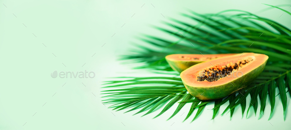 Exotic papaya fruit over tropical green palm leaves on turquoise background. Copy space. Pop art - Stock Photo - Images