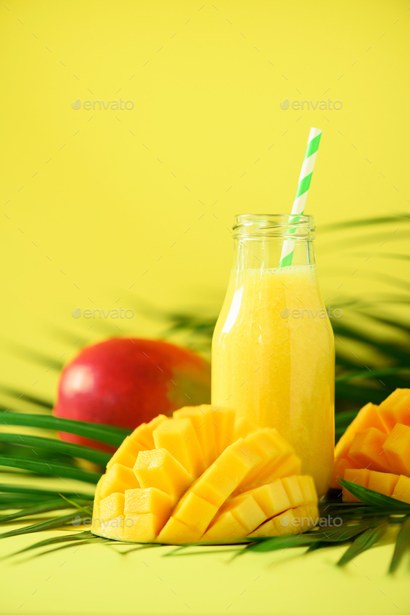 Delicious juicy smoothie with orange fruit and mango on yellow background.  Copy space. Pop art Stock Photo by jchizhe