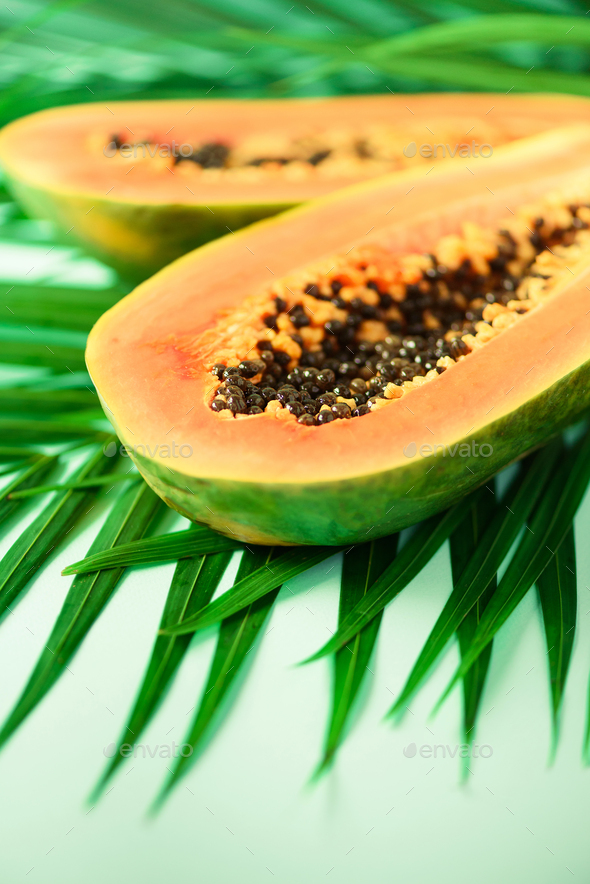 Exotic papaya fruit over tropical green palm leaves on turquoise background. Copy space. Pop art - Stock Photo - Images