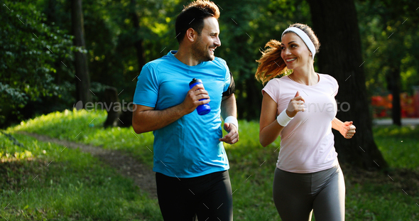 Happy couple jogging and running outdoors in nature Stock Photo by