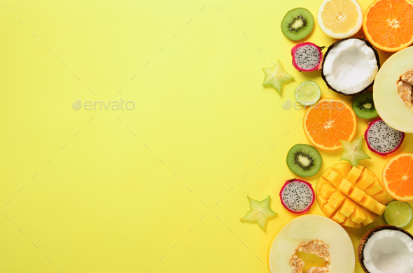 Exotic fruits on pastel yellow background - papaya, mango, pineapple, banana, carambola, dragon