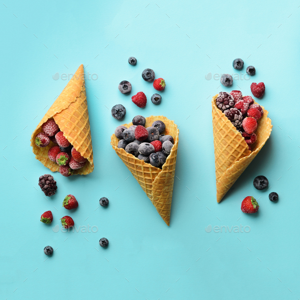 Frozen berries - strawberry, blueberry, blackberry, raspberry in waffle cones on blue background - Stock Photo - Images