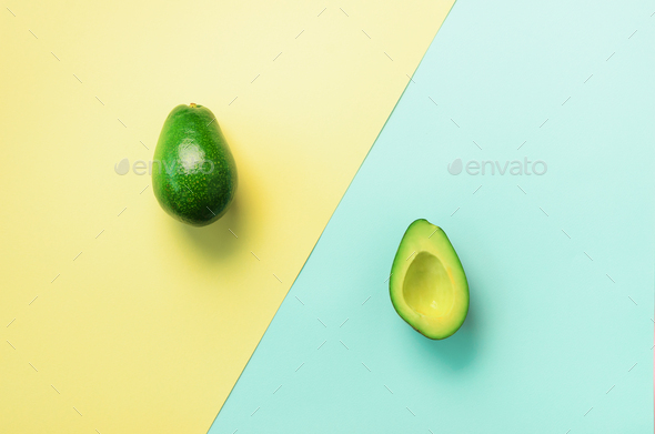 Avocado sliced with seed, whole fruit on blue and yellow background. Top view. Pop art design - Stock Photo - Images