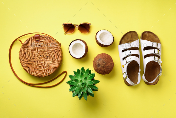 Stylish rattan bag, coconut, birkenstocks, palm branches, succulent, sunglasses on yellow background - Stock Photo - Images