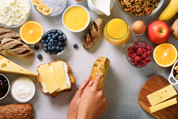 Female hands spreading butter on bread. Woman cooking breakfast. Healthy breakfast ingredients, food - Stock Photo - Images