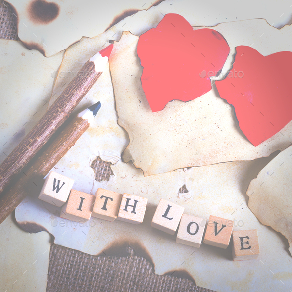 Old vintage sheet of paper, two red hearts, wooden pencils and words With love on cubes on burlap - Stock Photo - Images