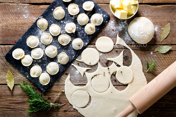Preparing, cooking, making homemade ravioli, pelmeni or dumplings with meat on wooden table top view - Stock Photo - Images