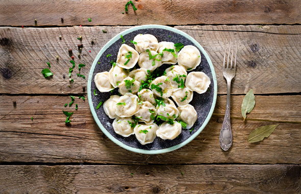 Boiled prepared homemade russian pelmeni, dumplings, ravioli with meat on grey plate with fresh - Stock Photo - Images