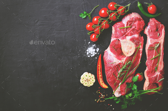 Raw fresh meat steak with cherry tomatoes, hot pepper, garlic, oil and herbs on dark stone, concrete - Stock Photo - Images