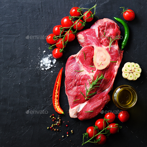 Raw fresh meat steak with cherry tomatoes, hot pepper, garlic, oil and herbs on dark stone, concrete - Stock Photo - Images