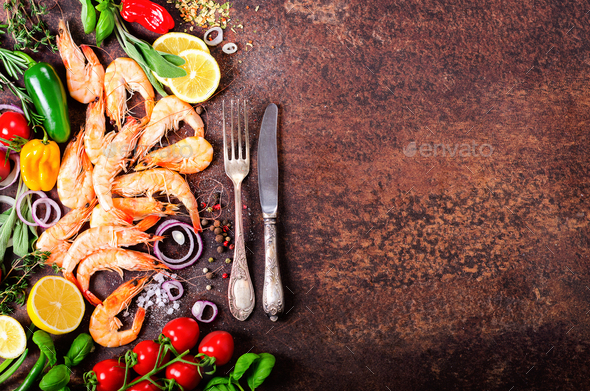 Fresh fish, shrimps with herbs, spices and vegetables on dark vintage background. Healthy food, diet