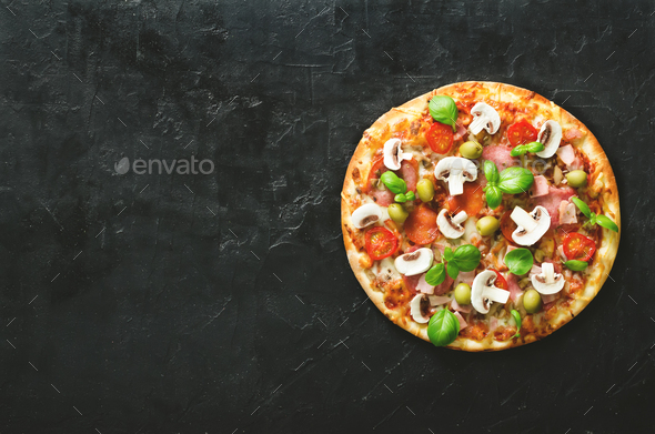 Fresh italian pizza with mushrooms, ham, tomatoes, cheese, olive, basil on black concrete background - Stock Photo - Images