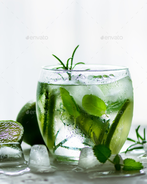 Homemade lime lemonade with cucumber, rosemary and ice, white background. Cold beverage for hot - Stock Photo - Images