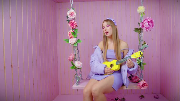 Sexy Blonde Girl Sit on Swing with Ukulele Sings alt