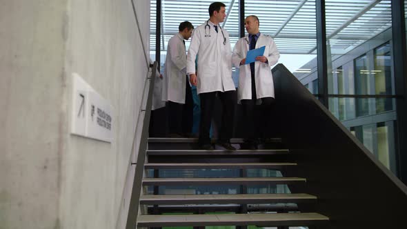 Team of doctors interacting while walking down stairs alt