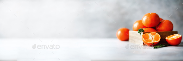 Orange tangerines, mandarins, clementines, citrus fruits with rosemary in wooden box on grey - Stock Photo - Images