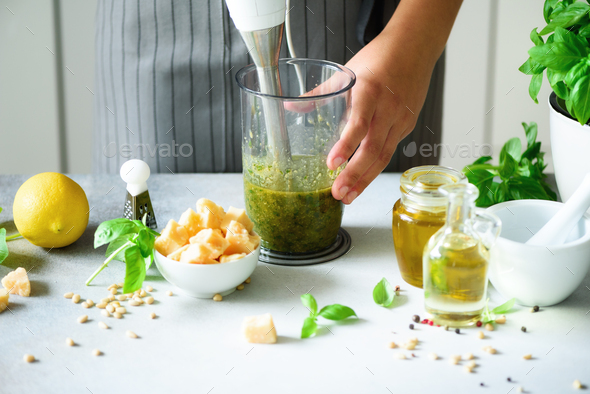Woman using hand blender to make pesto. White kitchen interior design. Copy space. Vegetarian, clean - Stock Photo - Images