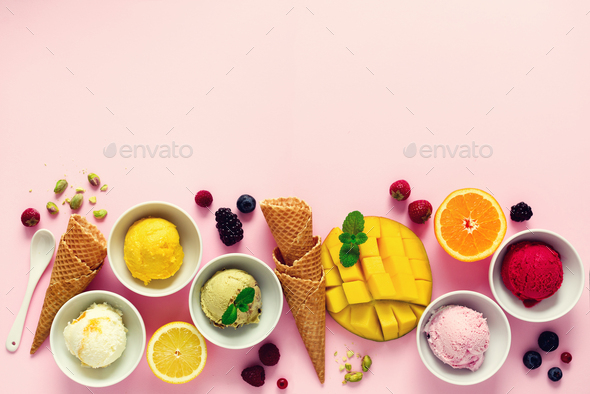 Ice cream balls in bowls, waffle cones, berries, orange, mango, pistachio on pink shabby chic - Stock Photo - Images