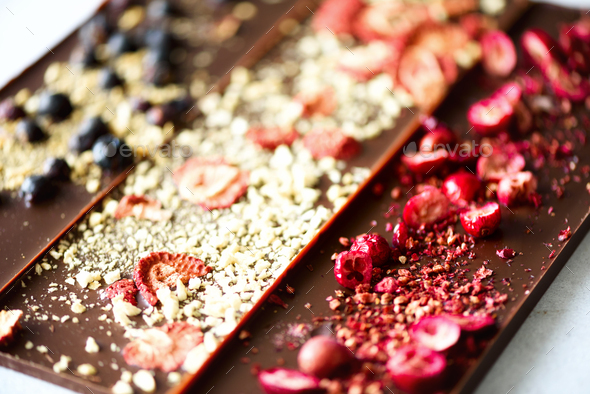 Handmade chocolate bars with dried cranberries, raspberries and pistachios, strawberries, nuts. Dark - Stock Photo - Images