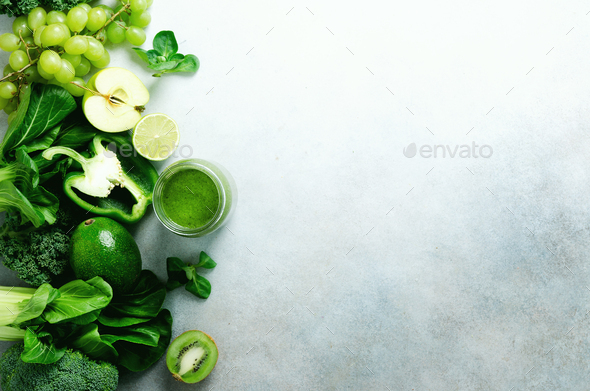 Green smoothie in glass jar with fresh organic green vegetables and fruits on grey background - Stock Photo - Images