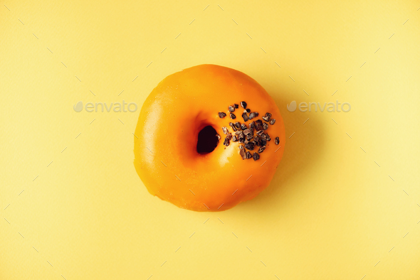 Sweet doughnut with orange glaze and chocolate on grey background. Tasty donut on pastel yellow - Stock Photo - Images