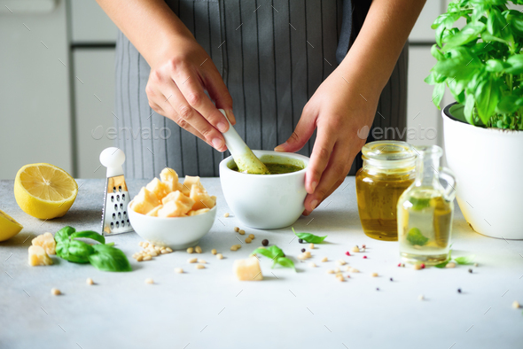 Woman hands making italian pesto in bowl. Ingredients - basil, lemon, parmesan, pine nuts, garlic - Stock Photo - Images