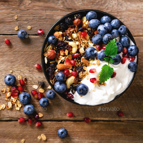 Tasty homemade granola, yogurt, fresh organic berries, pomegranate, mint on grey concrete background - Stock Photo - Images