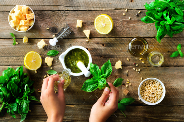 Woman hands making italian pesto in bowl. Ingredients - basil, lemon, parmesan, pine nuts, garlic - Stock Photo - Images