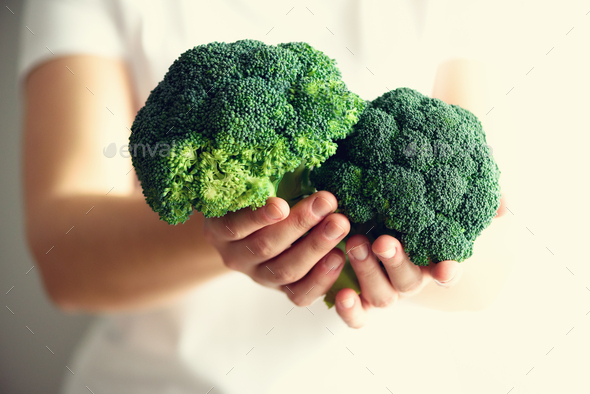 Woman in white T-shirt holding broccoli in hands. Copy space. Healthy clean detox eating concept - Stock Photo - Images