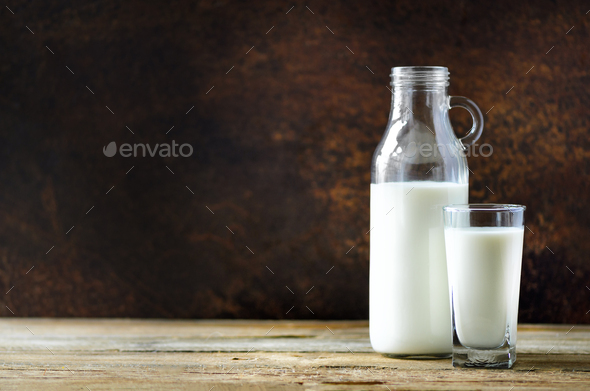 Milk bottle and glass on wooden table, dark background. Healthy eating concept. Copy space - Stock Photo - Images
