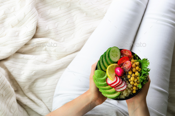 Girl holds in hands vegan, detox raw buddha bowl with avocado, quinoa, cucumber, radish, salad - Stock Photo - Images