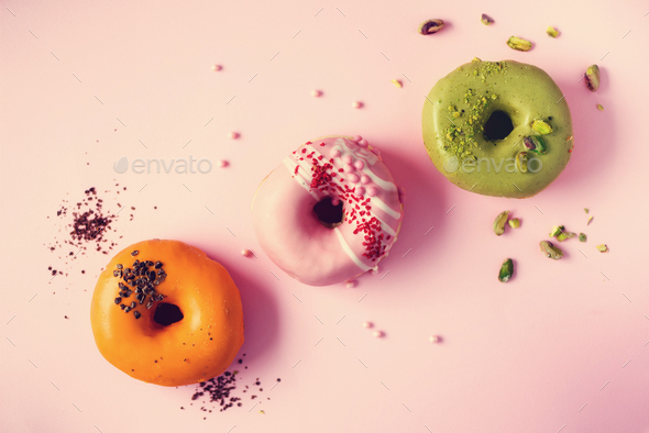 Colorful donuts with icing on pastel pink background. Sweet orange, green, pink doughnuts with - Stock Photo - Images