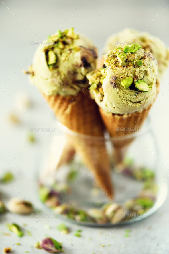 Green ice cream in waffle cone with chocolate and pistachio nuts on grey stone background. Summer - Stock Photo - Images