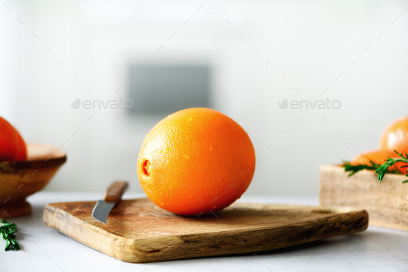 Citrus fruits background. Fresh fruits, rosemary. Big orange fruit with water drops, knife, wooden - Stock Photo - Images