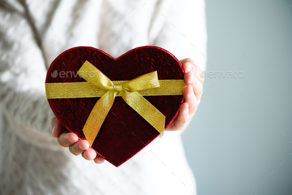 Female hands holding gift box heart shape on grey background. Copy space.  Love concept Stock Photo by jchizhe