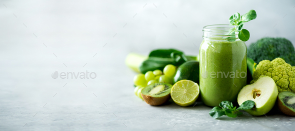 Glass jar mugs with green health smoothie, kale leaves, lime, apple, kiwi, grapes, banana, avocado - Stock Photo - Images