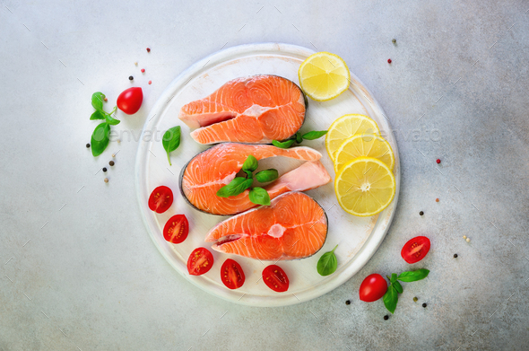 Salmon steaks with lemon, herbs, spices cherry tomatoes on grey concrete background. Healthy diet - Stock Photo - Images