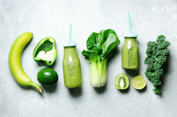 Green smoothie in glass jar with fresh organic green vegetables and fruits on grey background - Stock Photo - Images