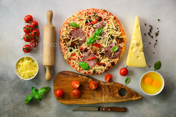 Food ingredients for italian pizza, cherry tomatoes, flour, cheese, basil, rolling pin, board, knife - Stock Photo - Images