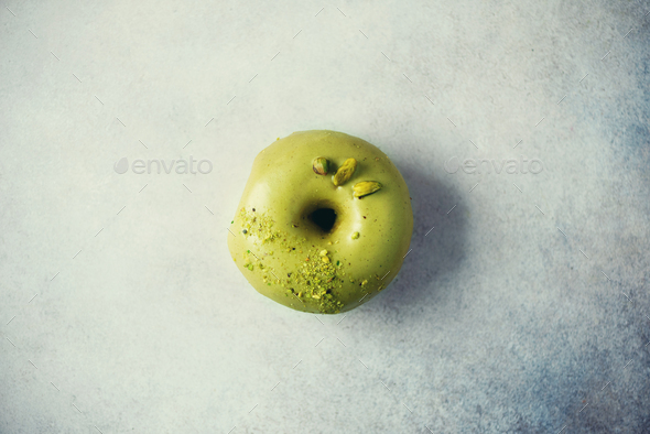 Sweet doughnut with green glaze and pistachio on grey background. Tasty donut on pastel concrete - Stock Photo - Images
