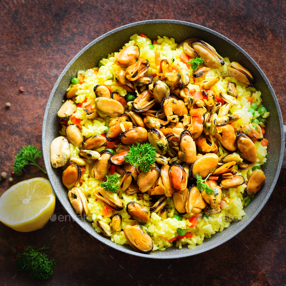 Traditional spanish seafood paella in pan rice, peas, shrimps, mussels, squid on light grey concrete - Stock Photo - Images